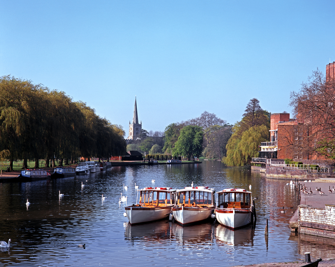River Avon with pleasure boats moored and Church to rear, Stratford-upon-Avon, Warwickshire, England, UK, Western Europe.